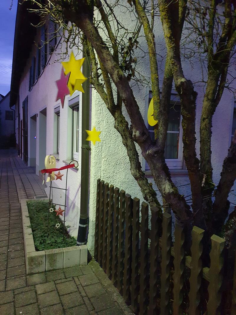 Weihnachtssterne an einem Baum an einer Hauswand in der Dämmerung