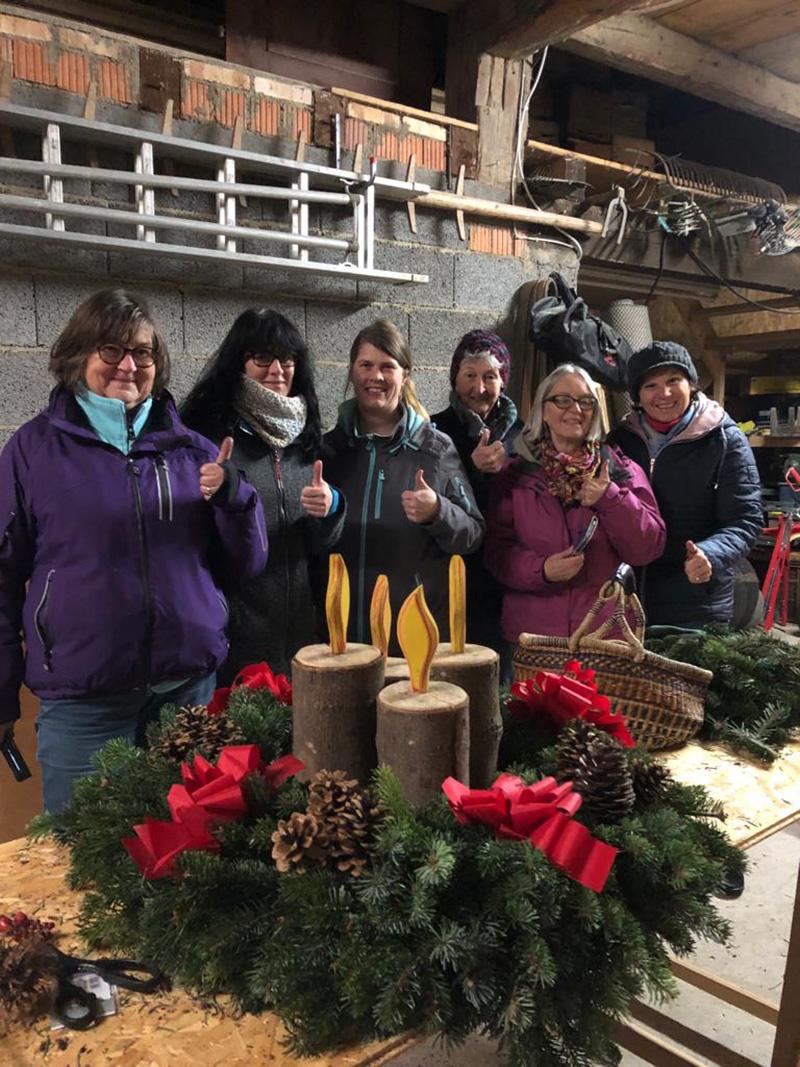 Frauen stehen hinter dem Adventskranz