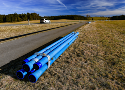 Blaue Rohre liegen am Straßenrand bereit, um für die neue Abwasserdruckleitung verwendet zu werden.