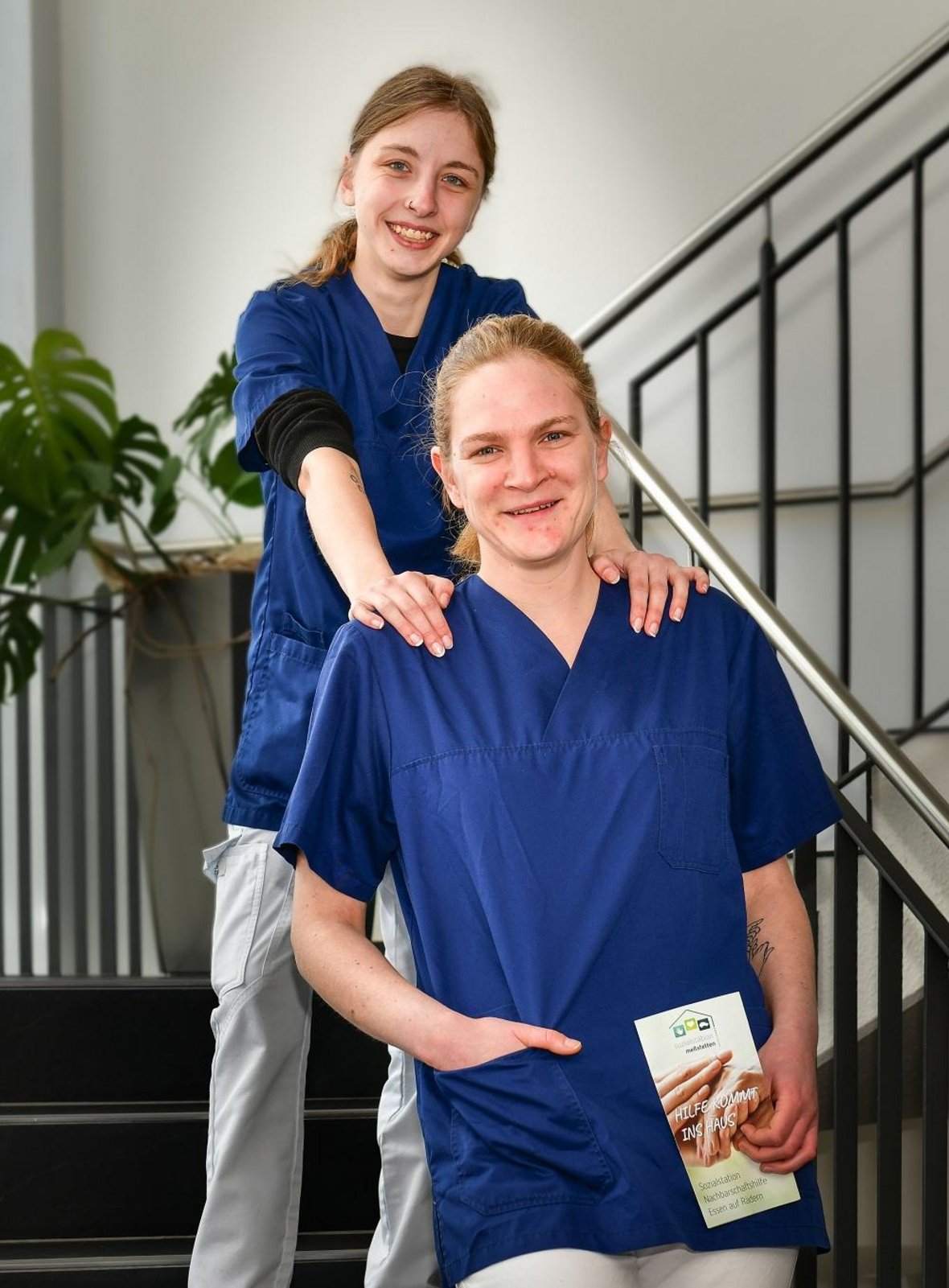 Zwei Pflegekräfte stehen gemeinsam auf der Treppe