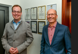 Bürgermeister Schroft und Jürgen Stengel stehen vor einer Wand mit vielen Urkunden und Diplomen.