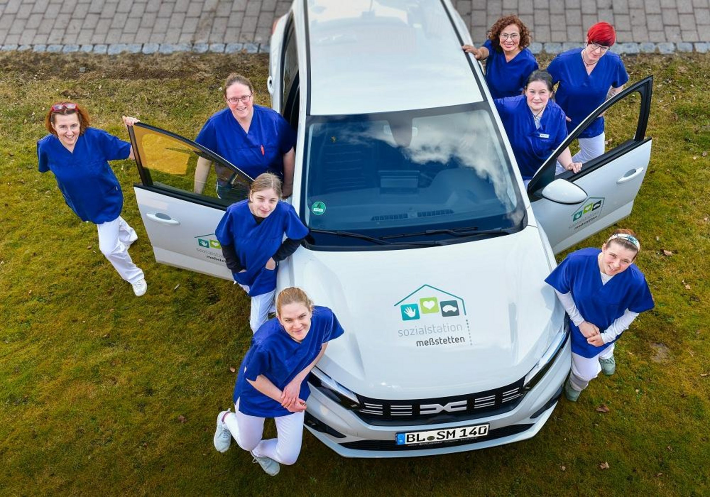 Angestellte der Sozialstation und ein Fahrzeug des Fuhrparks